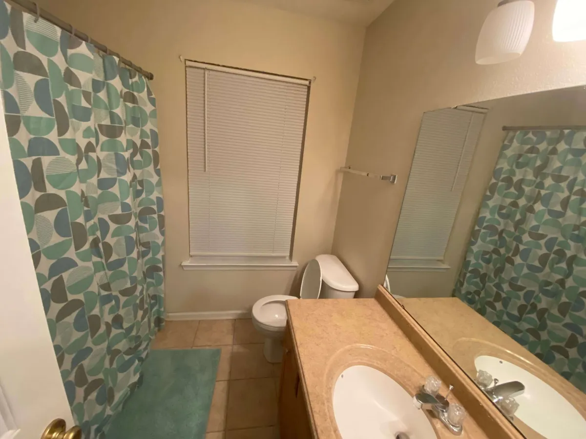 This image captures a bright bathroom featuring a well-lit vanity with a sink, an inviting shower curtain, a large mirror, and a window that adds a fresh, airy feel. Subtle decorative touches evoke an atmosphere of comfort and everyday ease, while the setup supports both quick routines and moments of personal care.