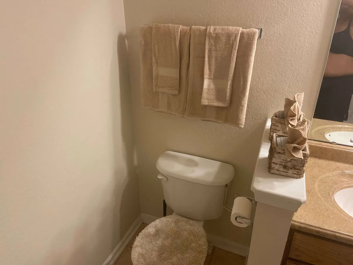 A cozy bathroom scene featuring a neatly arranged sink, toilet, plush towels, and decorative accents. The close attention to detail, such as the organized towels and tasteful decor, reflects the home’s commitment to guest comfort and convenience, making it inviting for daily routines or a moment of relaxation.