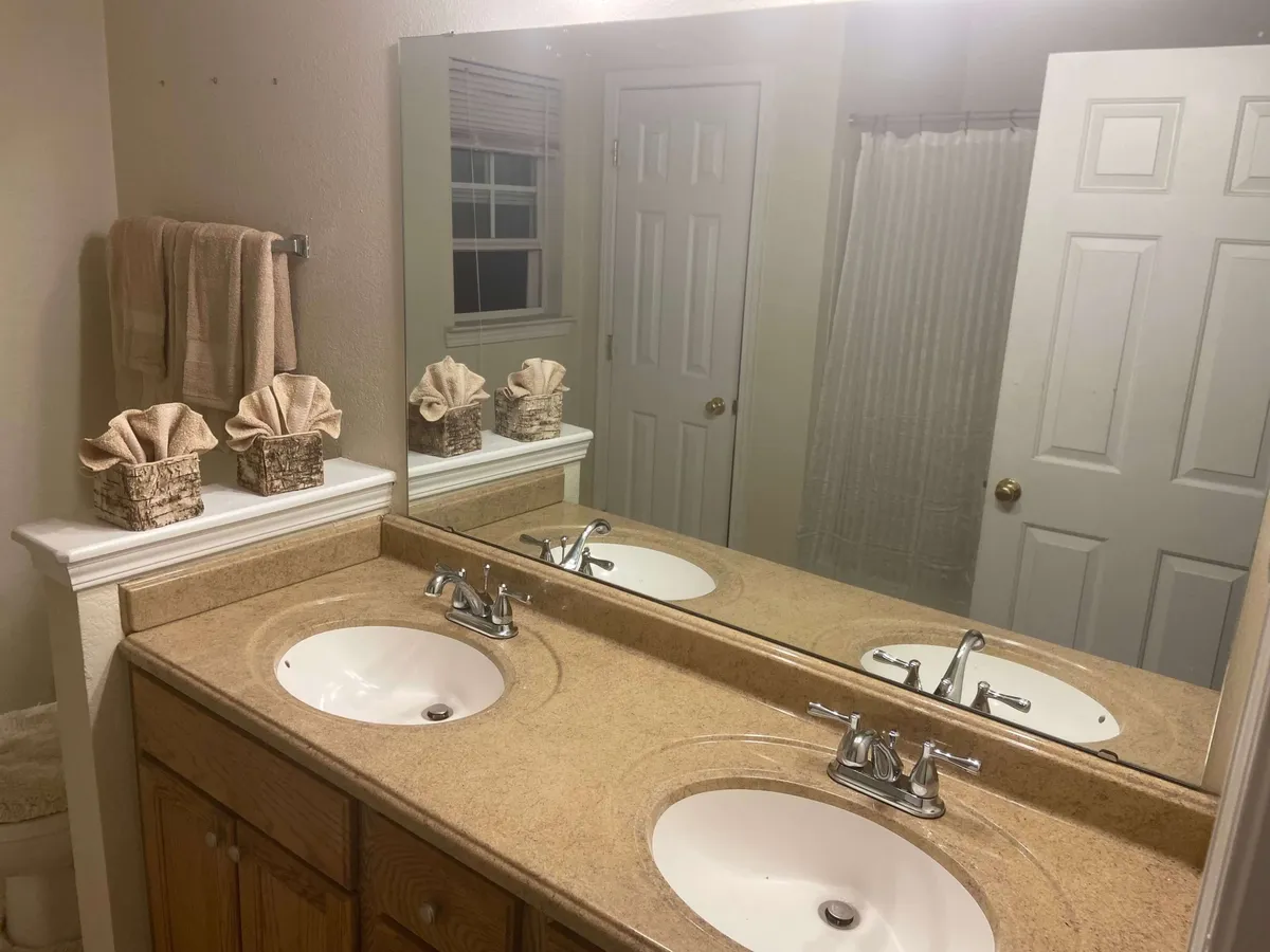 This image displays a thoughtfully designed bathroom with a double sink vanity, mirrored surfaces, and decorative storage baskets. The serene color palette and organized space invite a sense of calm, supporting morning or evening routines in privacy.